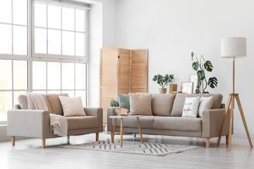 Interior of light living room with grey sofas, lamp and folding screen