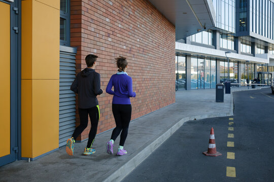 Man and woman jogging together near urban area building on a sunny day