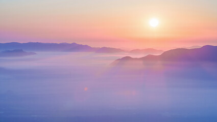 Fototapeta premium Sunrise over misty mountains with a soft glow illuminating the natural landscape beauty
