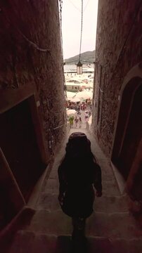 Young Woman Walking Through Picturesque Streets of Cinque Terre, Italy, Rear View in Colorful Mediterranean Village