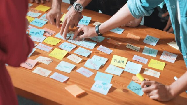 Top view of project manager sticking sticky notes and explain idea about web design. Professional marketing team or programmer brainstorming idea while looking at tablet with color palette. Symposium.