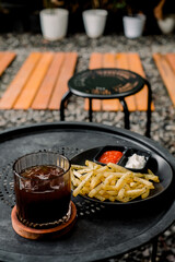 Coffee and fries on a cafe table. Casual dining with drink, golden french fries, ketchup, and mayonnaise. Vertical photo