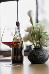 Bottle of rose champagne and wine glass is on table in the restaurant, flowers, wine cabinet,...