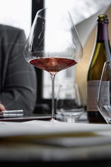 Bottle of rose champagne and wine glass is on table in the restaurant, flowers, wine cabinet, sparkling wine