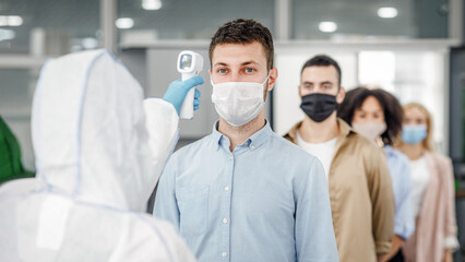 Modern technologies for determining temperature with non-contact thermometer. Man in hazmat suit...