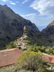 A popular view of Masca village in gorge: a triangular rock and a path leading to it along palm trees, illuminated by the rays of the dawn sun. Volcanic landscape of Tenerife, Canary Islands, Spain.