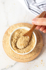 Hand is holding spoon with nutritional yeast flakes. Top view.