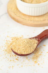 Nutritional yeast in wooden spoon. Close-up. Healthy vegan food, cheese substitute.