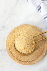 Nutritional yeast flakes in measuring cup. Top table view. Cheese substitute, vegan food.