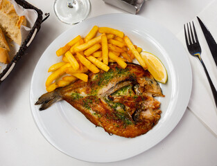 Appetizing grilled gilthead sea bream fish served with potatoes on platter