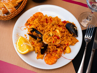 Paella made of rice and different seafood served in plate with other table appointments