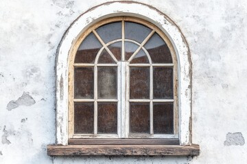 Obraz premium Arched window with weathered white frame set in a textured plaster wall of a building