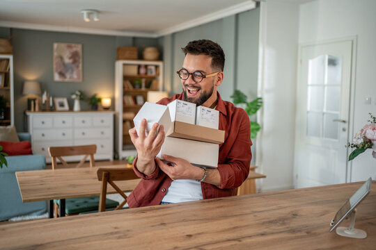 Happy man unboxing packages at home: receiving online orders