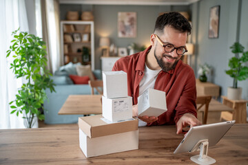 Small business owner preparing packages for shipping using digital tablet