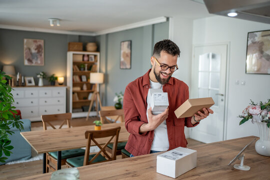 Happy man unboxing parcels at home in living room