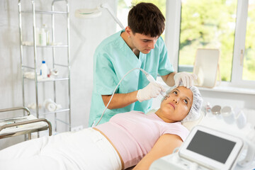 Fototapeta premium With precision and expertise, cosmetic doctor utilizes RF lifting attachment to deliver skin-tightening procedure, leaving client with visible and satisfying results.