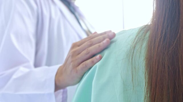 Female doctor's hands crossed her shoulders and gently touched her to encourage a female patient who was stressed from depression to help her relax.
