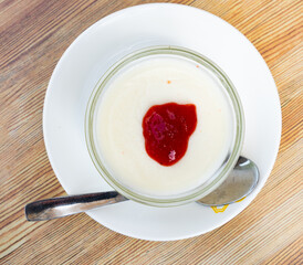 Italian dessert panna cotta with layer of pureed wild berries. Vanilla milk jelly in transparent glass.