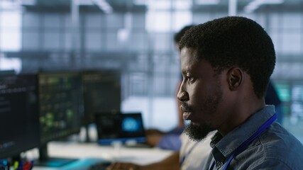 Software developers in data center implementing AI predictive maintenance systems. Focus on man in...