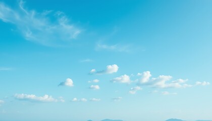 Serene blue sky with clouds and distant mountains.