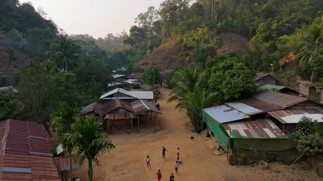 Game of volleyball in a peaceful ethnic village surrounded by green, Thailand. Aerial drone video