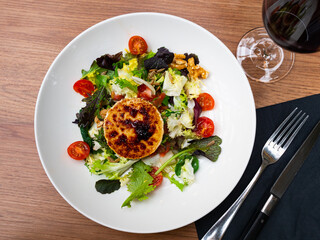 Fresh salad with goat cheese. Dish is made from leaves of Chinese and red cabbage, tomatoes, arugula and sunflower seeds.