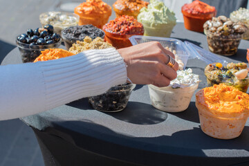 Woman's hand picking up a sample of fresh tzatziki sauce from a variety of dips and spreads...