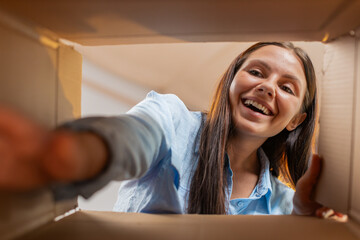 Happy woman unpacking delivery parcel at home. Smiling satisfied young girl shopper online shop...