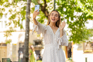Young pretty woman blogger taking selfie on smartphone, communicating video call online with...