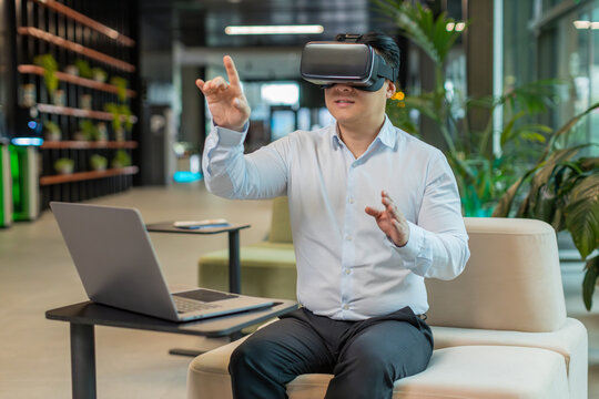 Middle-aged businessman programmer software developer using headset app making a presentation. Watching virtual reality 3D 360 video. Mature guy manager in shirt in VR goggles working at office lobby.