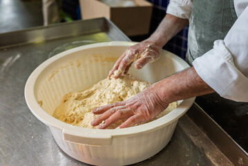 hands of a baker kneading bread, baker's hands developing dough texture