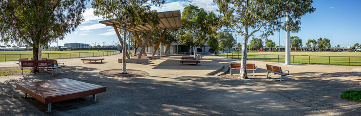 Panoramic view of a modern Australian public park with architectural shade structures, open...
