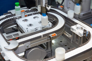 Medicine pills are filling in the bottle on production line machine conveyor at the medical factory