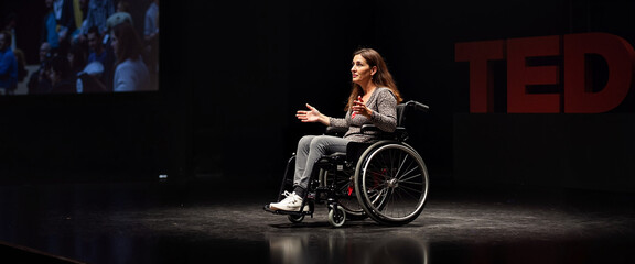 Woman in wheelchair speaking on TED stage
