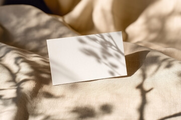 Blank ivory business card mockup on beige fabric with soft shadows and folds, natural cozy style for handmade or boutique branding