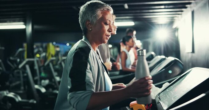 Mature, woman and treadmill in gym with smart watch, water bottle and towel for sweating with intense workout. Hydration, check progress time and fitness with machine, walking or steps for cardio