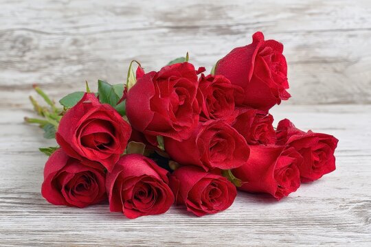 A vibrant bouquet of red roses on a rustic wooden surface.