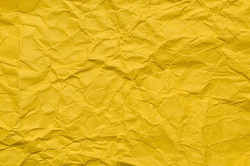 A textured yellow crumpled paper background with natural creases and folds. Ideal for design projects, digital graphics, or creative presentations requiring a vibrant