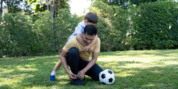 Activity: Father tying son's shoelaces before soccer play in the garden.