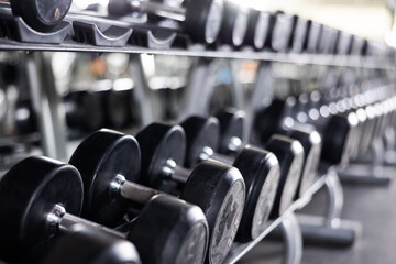 Fototapeta premium Dumbbells of different weights laid out on racks in gym