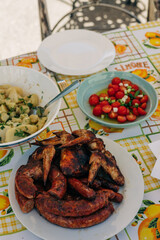 Grilled meats and fresh salad served at a rustic outdoor table during a sunny afternoon gathering