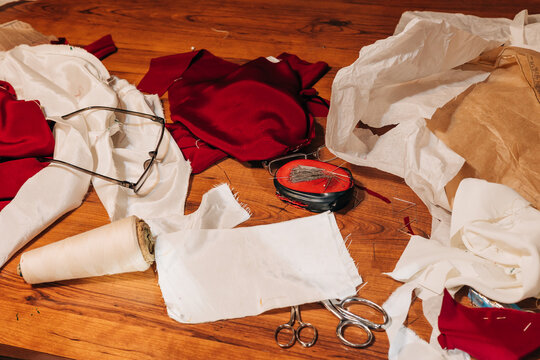 Crafting chaos in a sewing workspace with fabric remnants and tools scattered across a wooden table