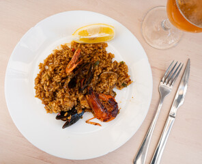 Paella made of rice and different seafood served in plate with other table appointments