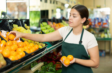 Female seller in apron takes mandarins from window.Concept of proper nutrition,healthy lifestyle