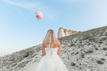 a woman in a white dress, a bride on a mountain with a blue sky. Beautiful nature, freedom, enjoyment of life. High quality photo