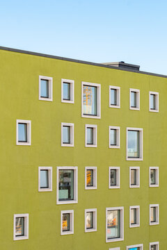 Apartment building with colorful green facade and small scattered windows, showing playful geometry and compact living design in Copenhagen, urban residential architecture.