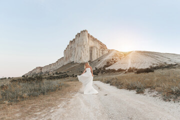 a woman in a white dress, a bride on a mountain with a blue sky. Beautiful nature, freedom, enjoyment of life. High quality photo