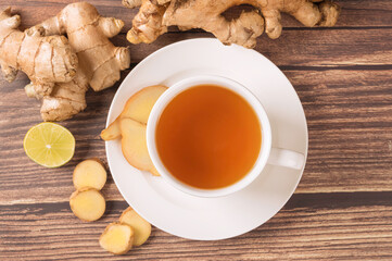 Cup of hot ginger tea and slices on wooden table. Top view
