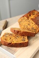 Cut homemade carrot cake with nuts and knife on table, closeup