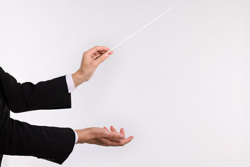 Conductor with baton on light grey background, closeup. Space for text